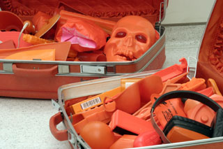 [Detritus and orange skull in suitcases]