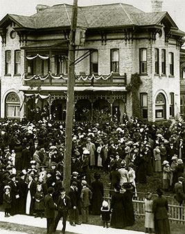 [Crowd on front lawn of venerable house]