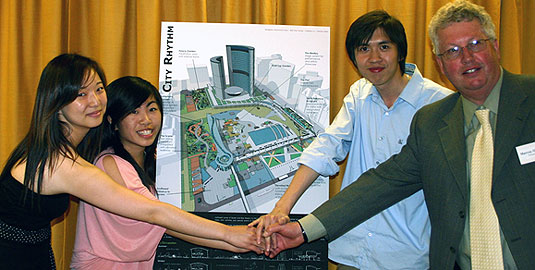 [Shaking hands in front of site plan]