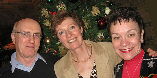 [Three happy faces in front of Christmas tree]