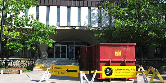[Signs and dumpster in front of library]