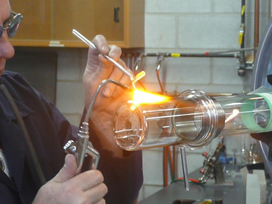 Ron Neill uses a breath-controlled device to melt glass.