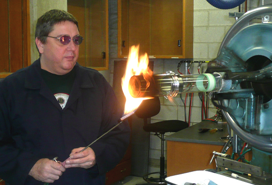Scientific glass blower Ron Neill heats up a glass container.