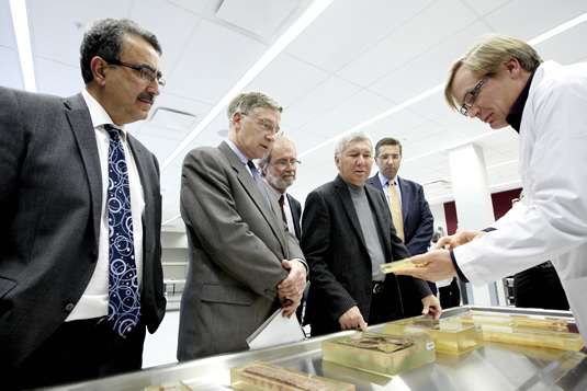 Feridun Hamdullahpur, Ken Seiling, Patrick Deane, Carl Zehr, and John Milloy look at specimens offered by Bruce Wainman in an anatomy lab.