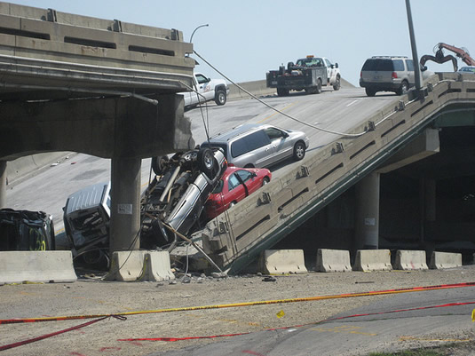 A bridge collapse with wrecked cars.