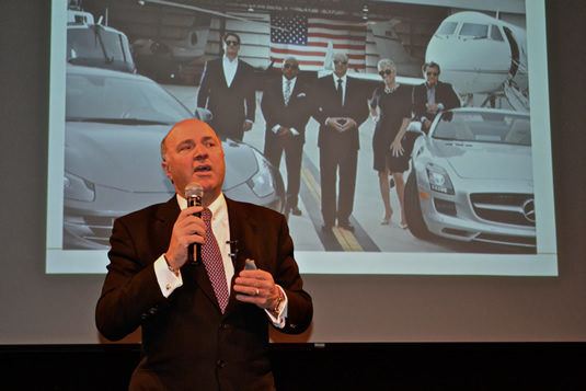 Kevin O'Leary speaks as a Shark Tank slide is displayed behind him.