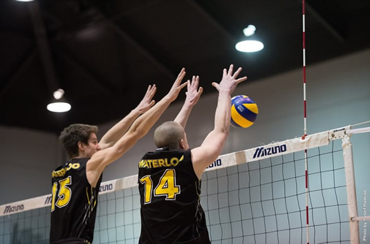 Members of the men's volleyball team jump to intercept an incoming ball.