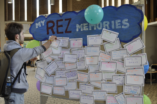 A student adds a handwritten residence memory to a bulletin board in the Student Life Centre.