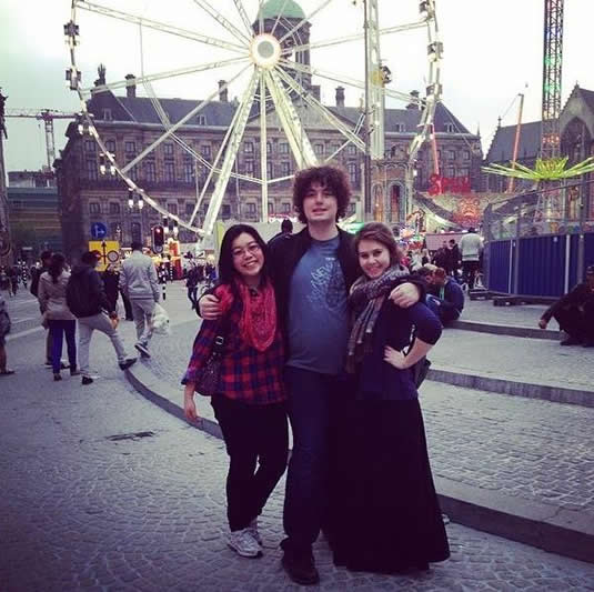 Three students pose in front of a carnival in Dam Square.