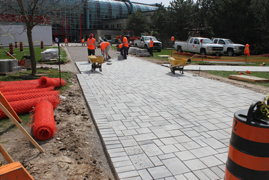 Workers assemble interlocking blocks on the pathway between MC and DC.