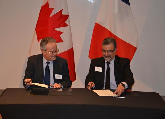 Laurent Servant and Feridun Hamdullahpur sign a chemistry partnership agreement in front of the Canadian and French flags.