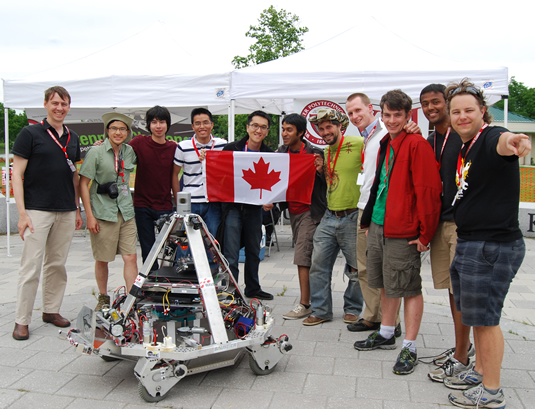 Members of the UW Robotics Team pose with the Canadian Flag and their robot.