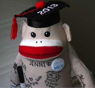 A stuffed monkey wearing a mortarboard hat and a residence button.