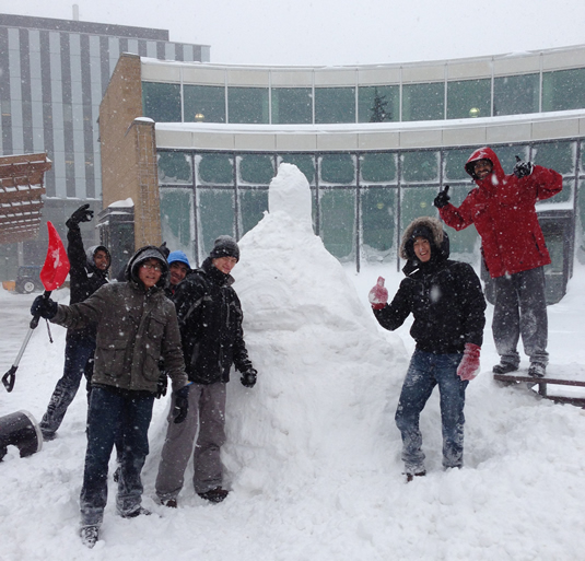 Students in the process of building a snowman in the SLC courtyard.