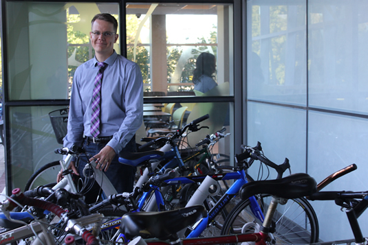 Professor Markus Moos poses with a crowded bike rack full of bicycles.