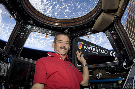 Chris Hadfield holds at uWaterloo pennant aboard the International Space Station.